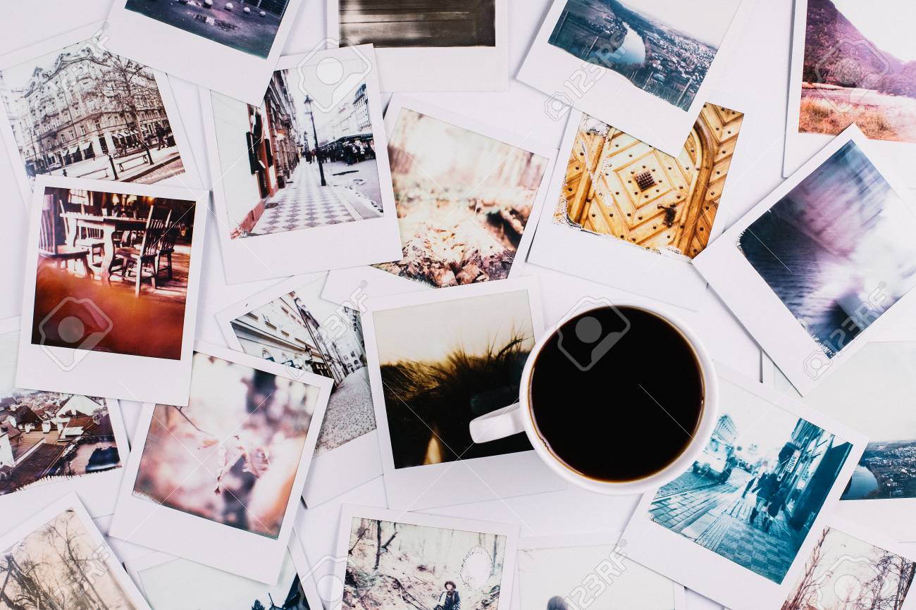 A mug with coffee standing between a bunch of polaroids